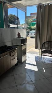 a kitchen with a stove and a table and a chair at Pousada Azambuja in Cidreira