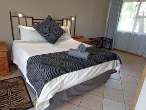 a bed with a black and white comforter and pillows at Ingwe Guest lodge in Vanderbijlpark +1 photo