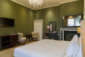 a bedroom with green walls and a bed and a desk at Stoke Place- Part of the Cairn Collection in Slough