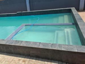 a swimming pool with a hose in the water at Eden Villas Guesthouse in Kuruman +15 photos