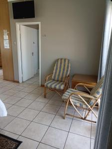 a living room with two chairs and a television at Ingwe Guest lodge in Vanderbijlpark