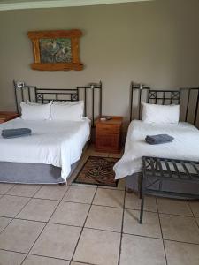 two beds in a room with a tiled floor at Ingwe Guest lodge in Vanderbijlpark