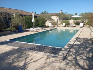 a swimming pool in a yard with chairs and an umbrella at Résidence de vacances avec piscine in Aiguèze