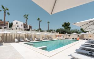 a swimming pool with lounge chairs and umbrellas at Helios Blue Villas Kriopigi Kassandra in Kriopigi