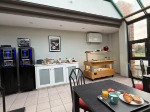 a kitchen with a table and a counter with food on it at Cit'Hotel LA PYRAMIDE in Romorantin