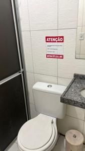 a bathroom with a toilet and a sign on the wall at Hotel Santiago Juazeiro in Juazeiro do Norte