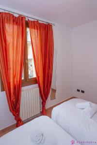 a bedroom with two beds and an orange curtain at Casa da Luna in Parma