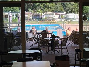 a patio with tables and chairs and a swimming pool at Camping San Lanaco in Lanaken