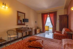 a bedroom with a bed and a desk and a chair at Hotel A Pinnata in Lipari