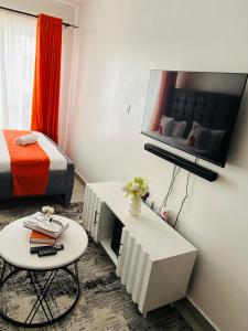 a room with a bed and a table and a tv at Tusmo homes in Ongata Rongai 