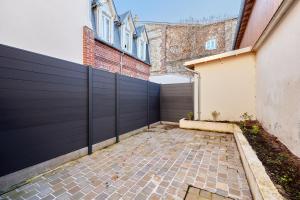 a garage with a black fence and a driveway at Jeanne d'Arc - Plage à pied - Central in Villerville