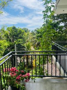 a balcony with flowers and a view of the forest at Mama Place in Hikkaduwa