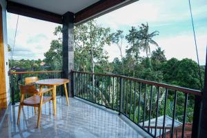 a balcony with a table and a view of the forest at Sandat Garden House in Ubud