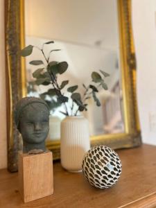 a bust and a vase on a table with a mirror at Entre Mer et Dunes de Pin in Neufchâtel-Hardelot