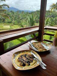 two plates of food on a wooden table with a view at Forest Side Bungalow in Tetebatu +101 photos