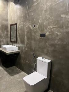 a bathroom with a white toilet and a sink at Mama Place in Hikkaduwa