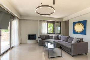 a living room with a couch and a glass table at Helios Blue Villas Kriopigi Kassandra in Kriopigi