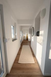 a hallway with white walls and wood floors and a mirror at Seeblick-Apartment am Bodensee bei Konstanz mit großer Terrasse in Reichenau