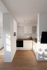 a kitchen with white cabinets and a black appliance at Seeblick-Apartment am Bodensee bei Konstanz mit großer Terrasse in Reichenau