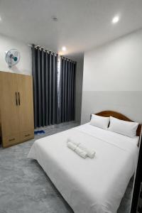 a bedroom with a large white bed and a fan at Motel Mai Thu in Thăng Bình