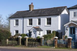 a white house with a fence in front of it at Hatchet Pond Cottage in Beaulieu