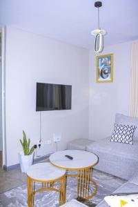 a living room with a couch and a table at TanuStays - Modern 1 Bedroom at Royal Suburbs Tsavo, near TRM in Nairobi