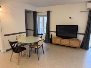 a living room with a table and a television at Le Petit Sancerrois in Sancerre