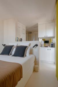 a white bedroom with a large bed and a kitchen at MiHotel - La Maison Rose in Lyon