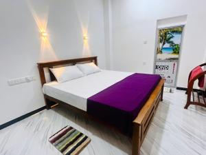 a bedroom with a large bed with a purple blanket at Bluebell Guest House in Unawatuna