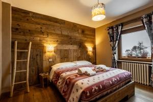 a bedroom with a bed with a wooden wall at Chalet Saint-Barthélemy Hotel in Nus