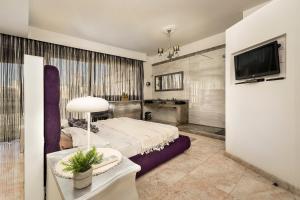 a bedroom with a bed and a table and a tv at Cherry Penthouse in Spinola Bay in St. Julianʼs