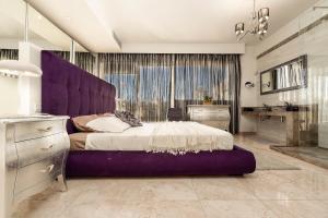 a large bed with a purple headboard in a bedroom at Cherry Penthouse in Spinola Bay in St. Julianʼs