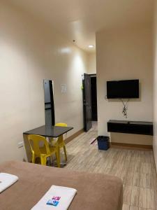 a room with a table and yellow chairs and a flat screen tv at Zion Pension House in Ozamis