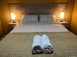 a bed with two towels on it with two lamps at Cabaña del Llicanko in Achao
