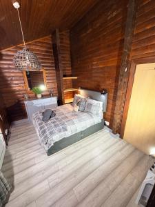 a bedroom with a bed and a wooden wall at Antler Lodge Traditional Log Cabin in Dunoon