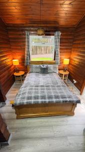 a large bed in a wooden room with two lamps at Antler Lodge Traditional Log Cabin in Dunoon +5 photos