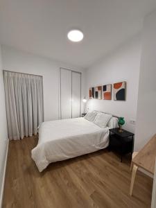 a white bedroom with a bed and a wooden floor at Cuatro Cantillos in Aguilar de la Frontera