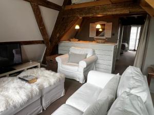 a living room with two white couches and a tv at De Waterzooi Suites in Ghent