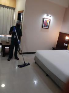 a man with a vacuum cleaner in a bedroom at Hotel Mirabel in Jajpur Road