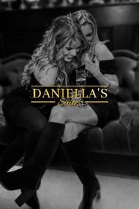 two women are sitting on a couch holding drinks at Daniella's Suites in Peabody