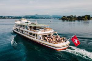 a boat with a canadian flag on the water at Horizon 62 I Zürich Lakeside Apartment I Modern I Free Parking I Self-Check-In in Richterswil