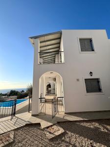 a white house with a balcony and a pool at Three Olive Homes in Kalymnos