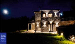 a stone house with lights on it at night at Orraon Luxury Villa - Exclusive retreat with panoramic views and infinity pool in Lefkada