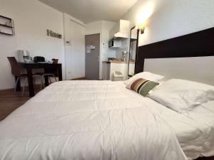 a large white bed in a room with a table at Studio avec piscine SAINT FLORENT - FLO300-259 in Saint-Florent +10 photos