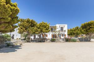 a large white house with trees in front of it at ĪKADE Mykonos in Mikonos