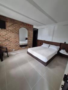 a bedroom with a bed and a brick wall at Hotel Casa Bambu in Calima