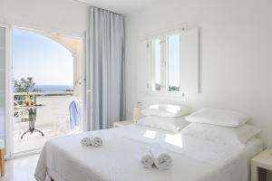 a white bedroom with a bed and a large window at Villa Anthemoessa - Endless Seaview in Pythagoreio