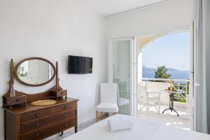 a bedroom with a mirror and a dresser and a balcony at Villa Anthemoessa - Endless Seaview in Pythagoreio