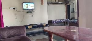 a room with a table and a tv on a wall at Danny's Homestay Coorg in Madikeri +2 photos