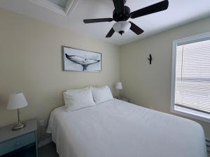 a bedroom with a white bed and a ceiling fan at Drift Ashore House in Rocky Harbour